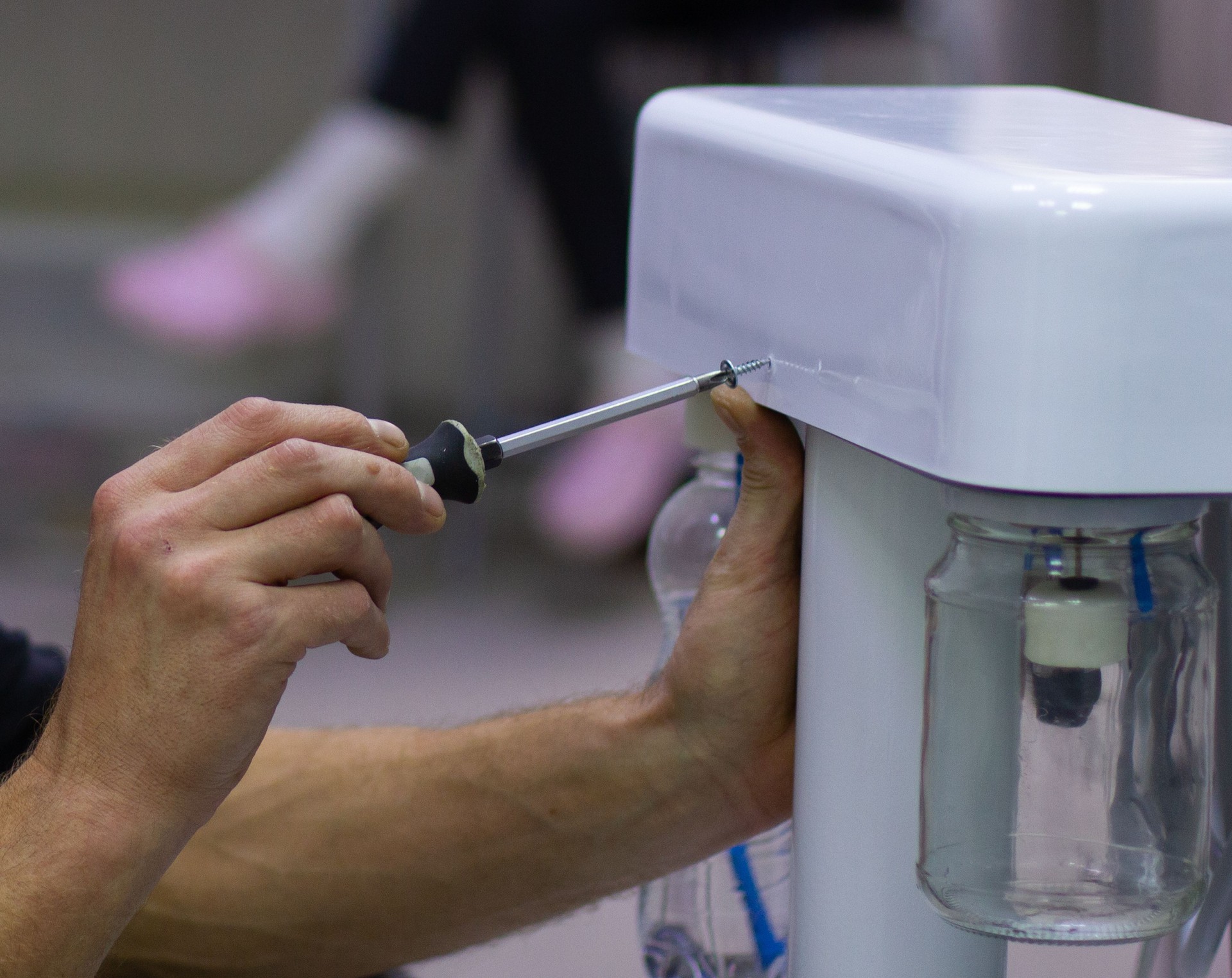 Mekhanki repairs medical equipment. The master tightens the bolts in the body of the medical equipment with a screwdriver, installing it and preparing it for work.