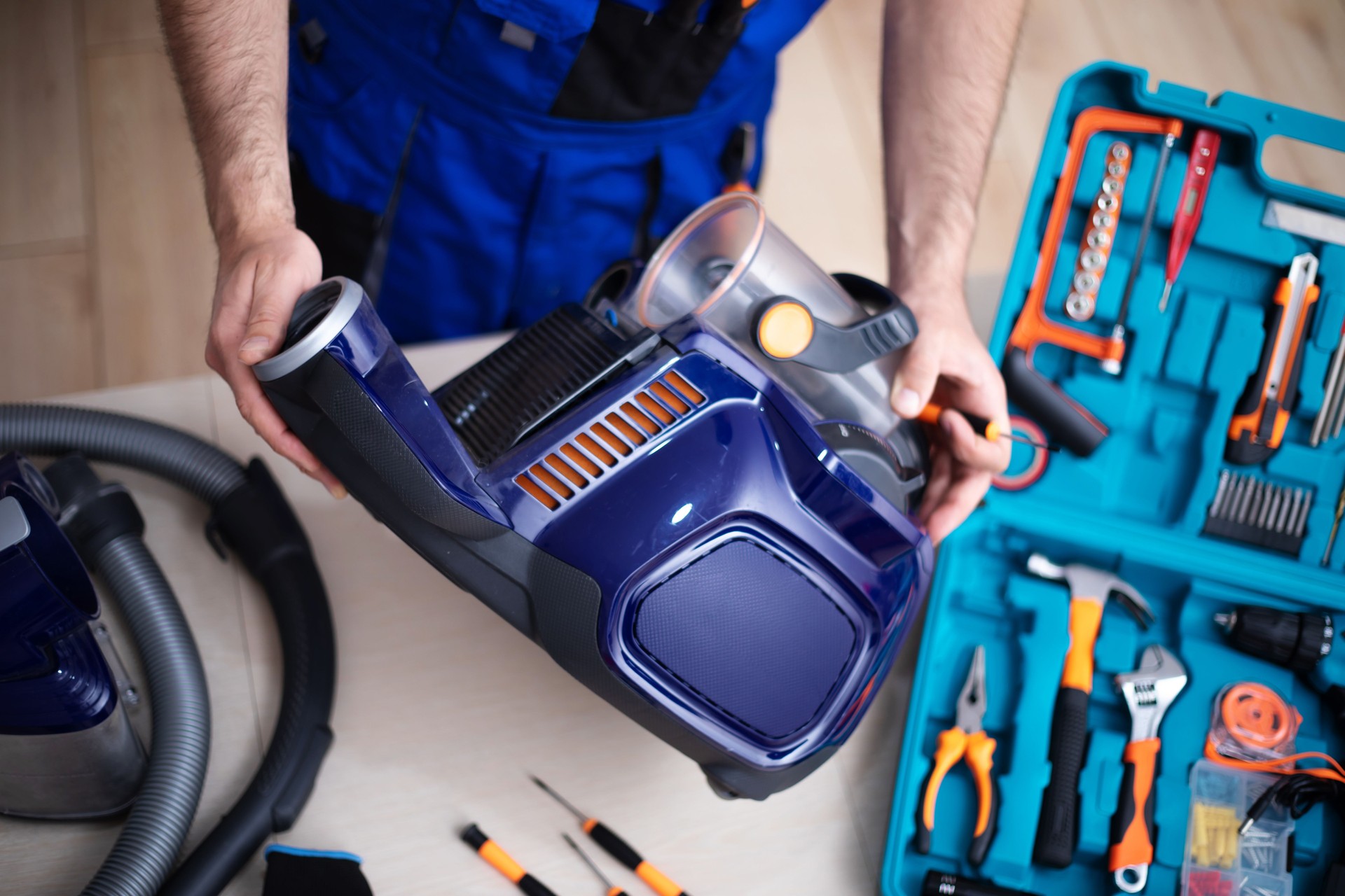 Handsome young serviceman is repairing modern vacuum cleaner in his office