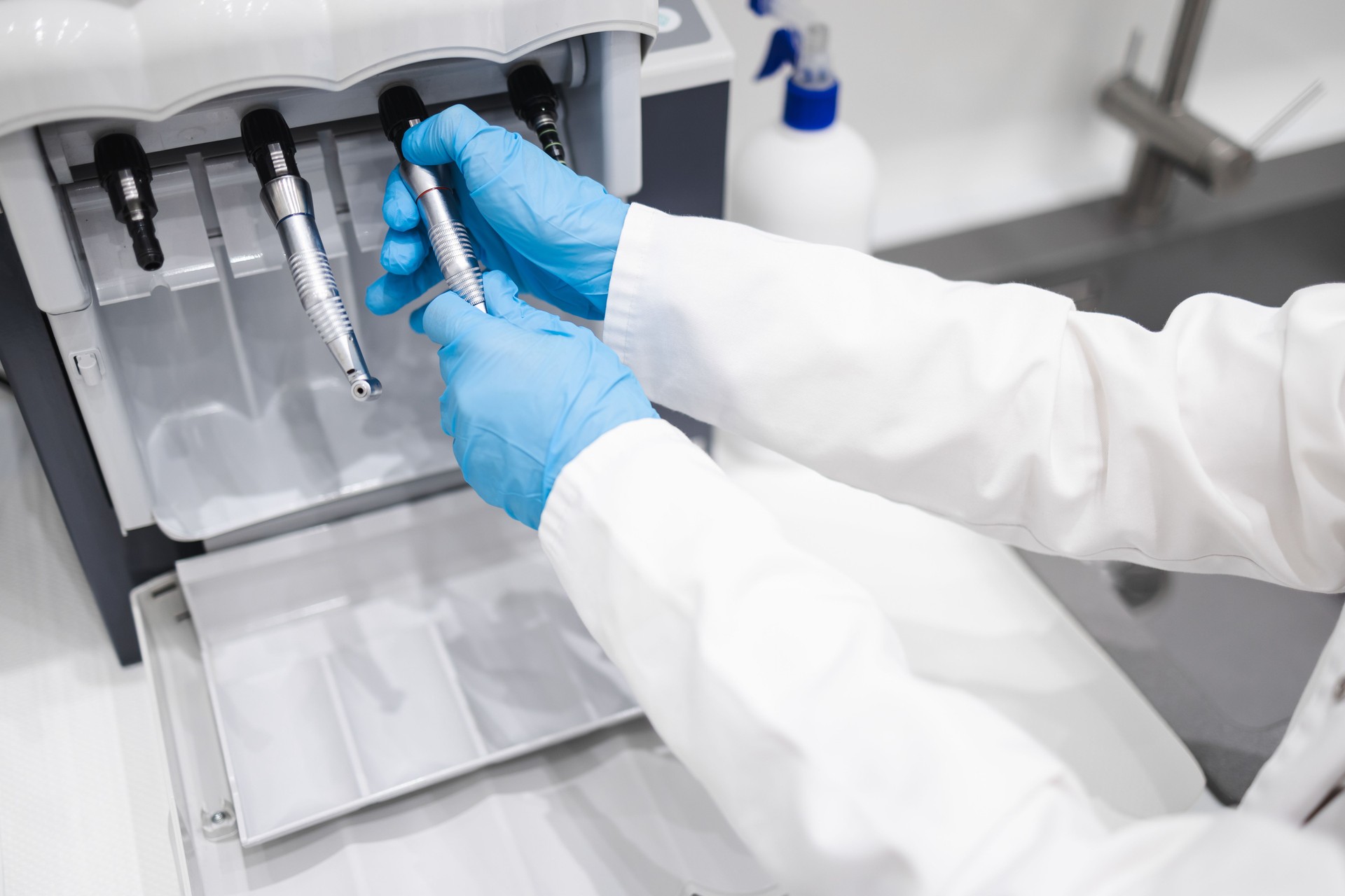 Close up of dental worker cleans and lubricates dental handpieces on a special machine